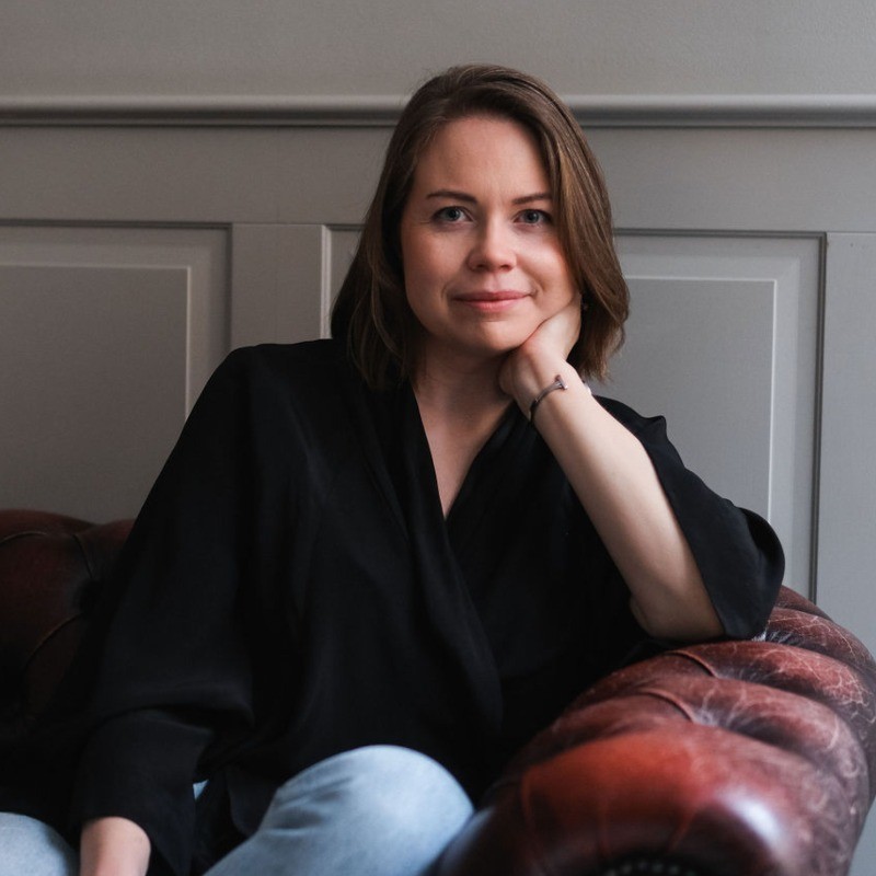 Knacks rekryteringskonsult Sara Avedal sitter avslappnat i en fåtölj, hon stöttar huvudet i handen och småler mot kameran.