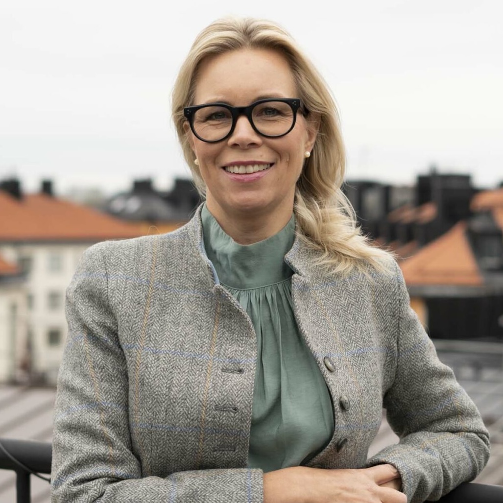 Den nyrekryterade CMOn Jeanette Eliasson står högt upp, kanske på ett tak, med vad som ser ut som Stockholm i bakgrunden. Hon tittar rakt in i kameran och ler.